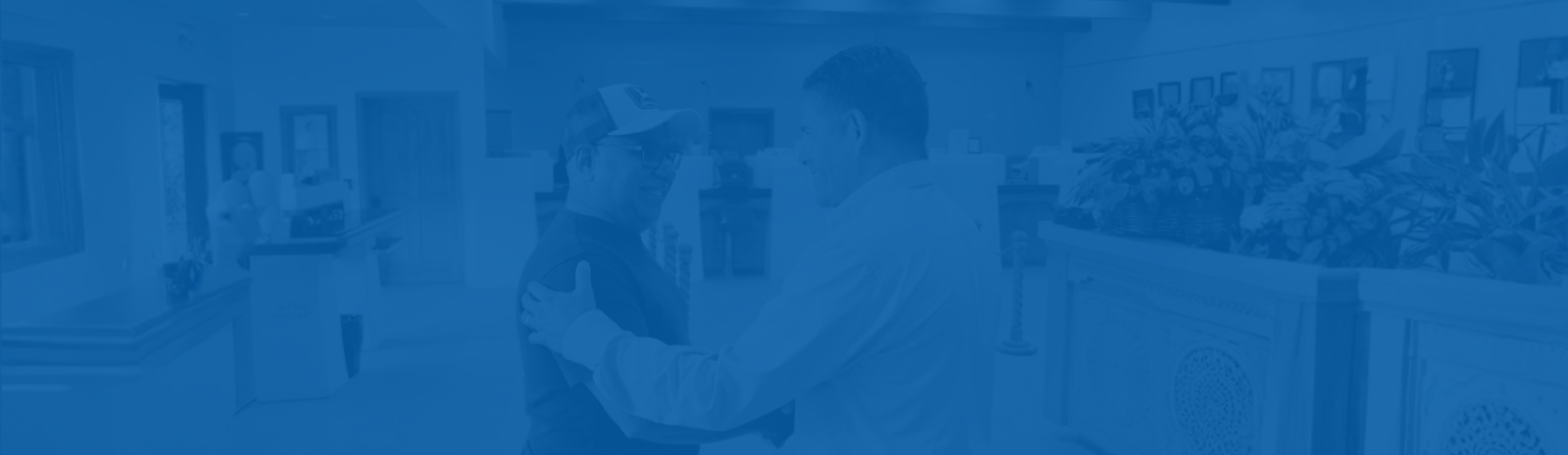 Michael Silva business customer shaking hands with Angel Reyes bank CEO in main office lobby.